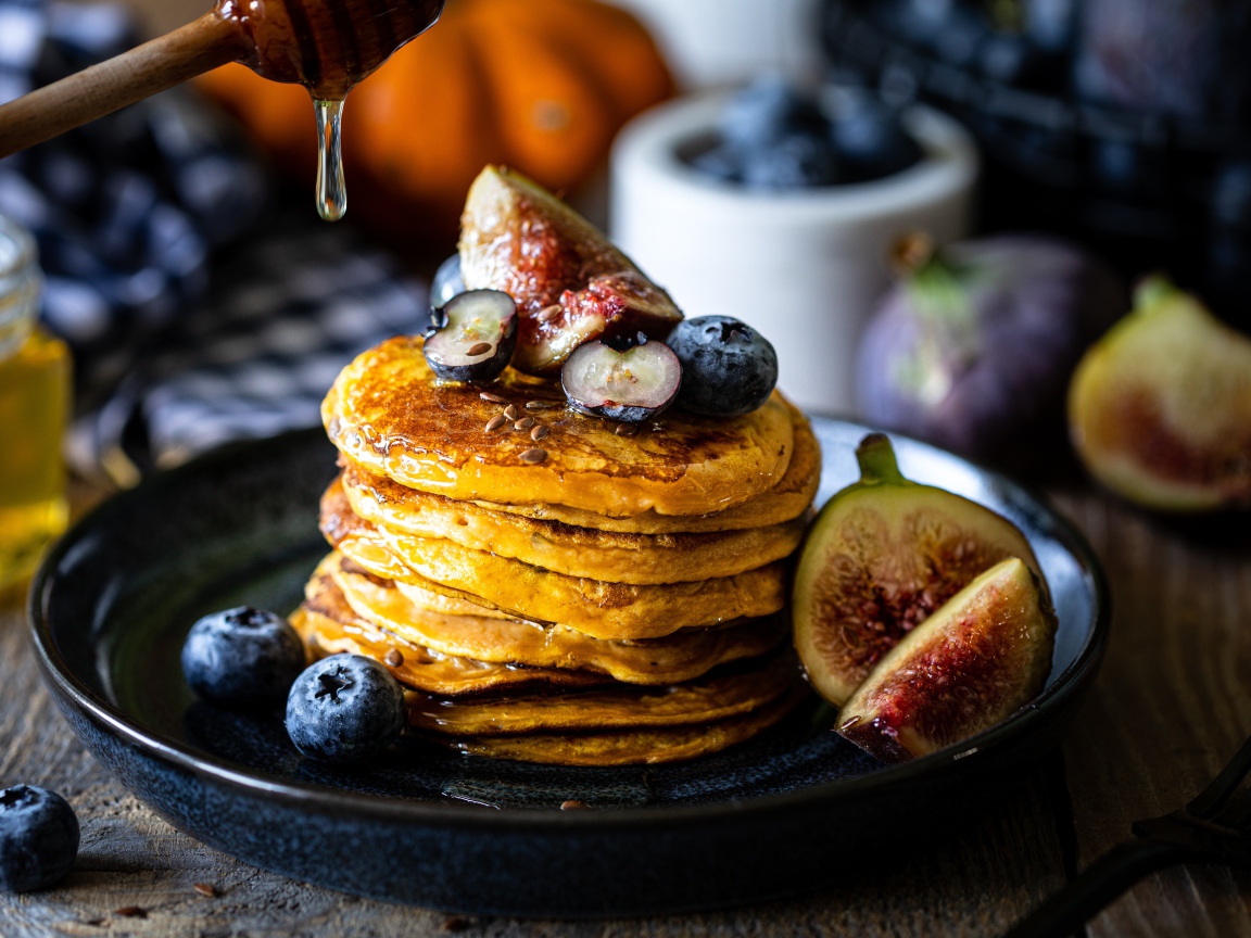 Аппетитные оладьи на тарелке с ягодами черники и инжиром