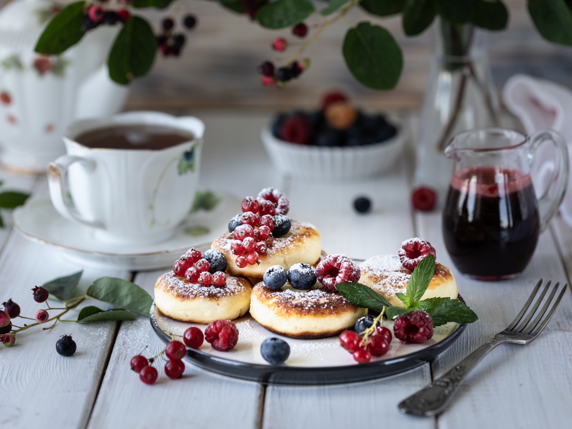 Сырники на столе с ягодами и чаем на завтрак