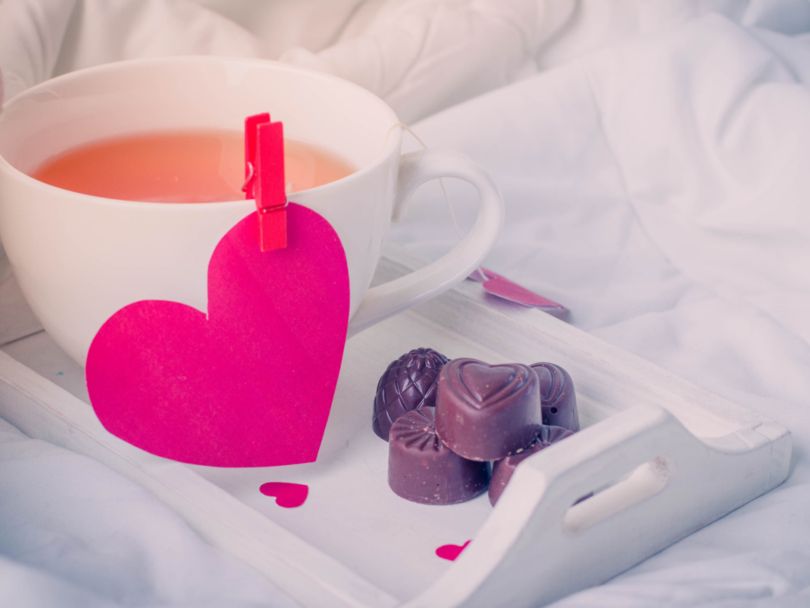 Чашка кофе с красным сердцем и шоколадными конфетами 