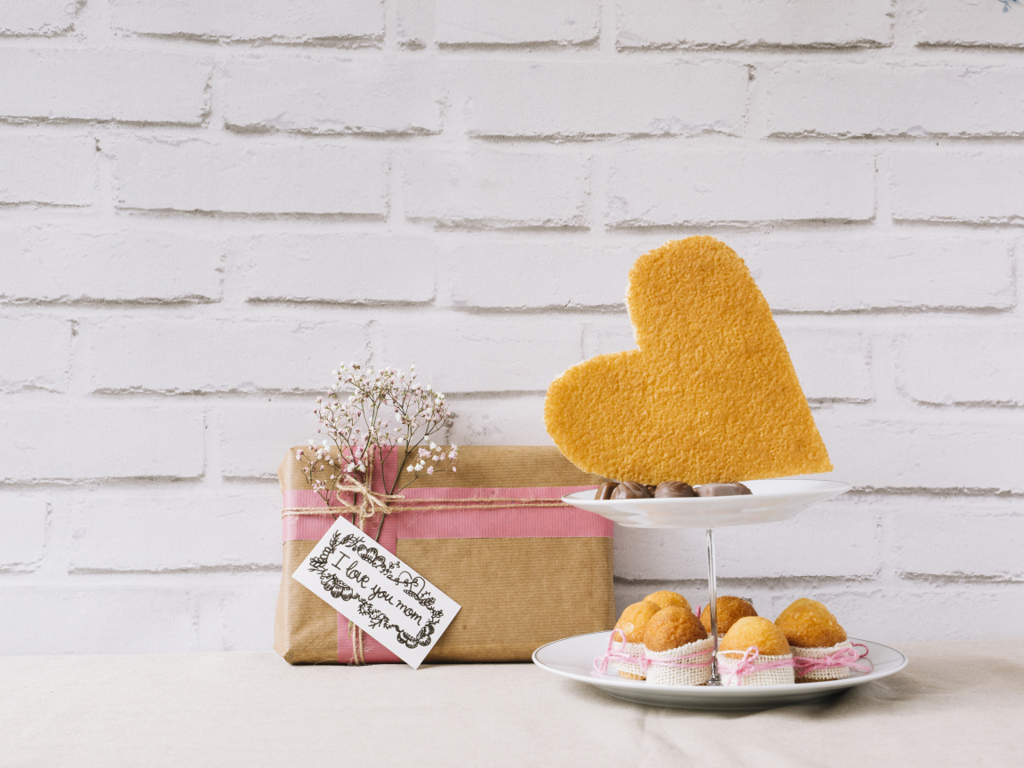 Кексы на тарелке на столе с подарком для любимой 