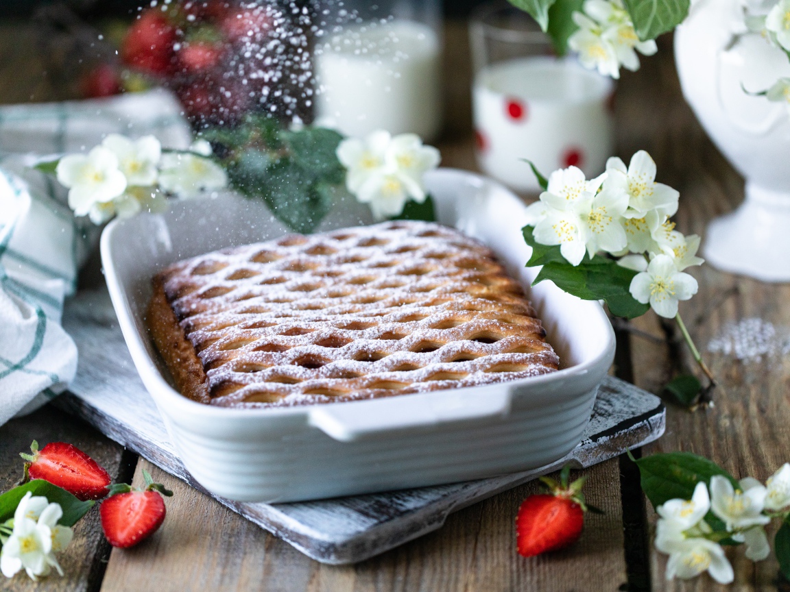Вкусный клубничный пирог с сахарной пудрой на столе с цветами жасмина