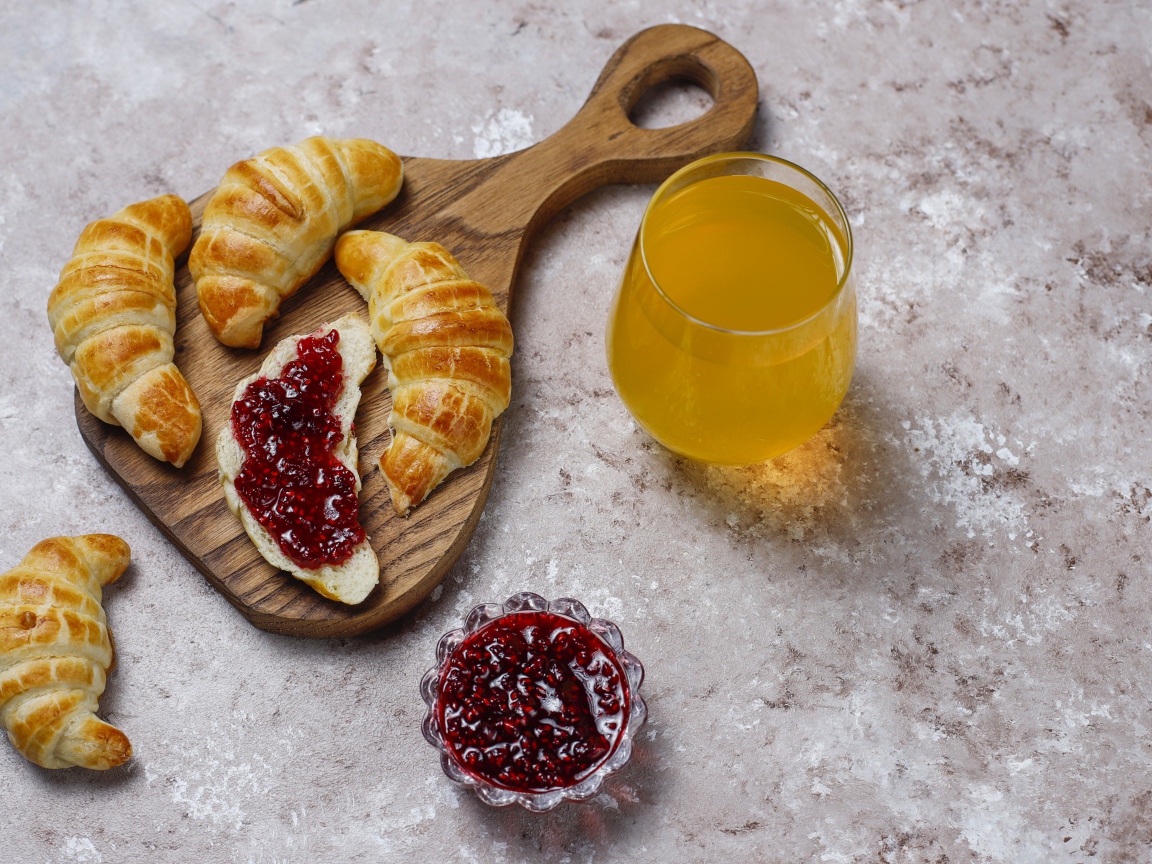Сок на столе с круассанами и джемом