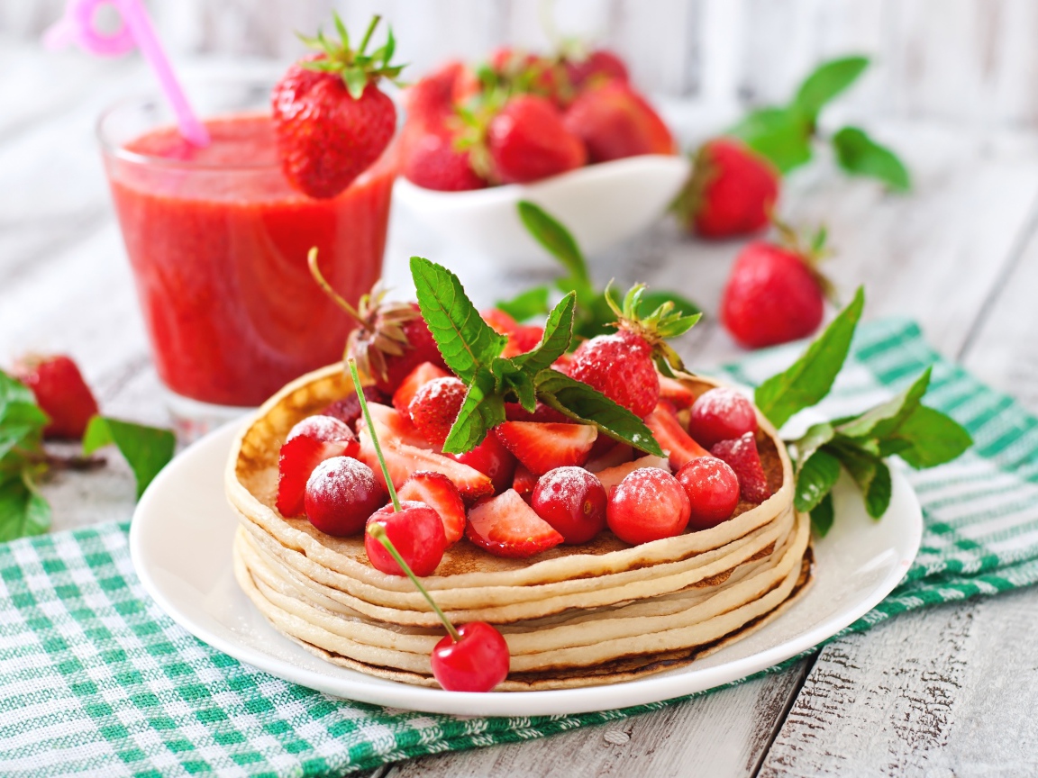 Блины с ягодами клубники  и черешни на белой тарелке