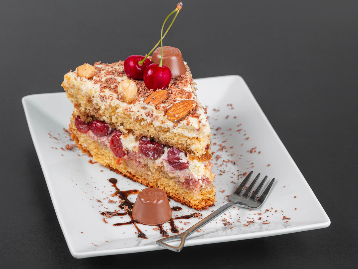 Кусок торта с ягодами вишни и миндальным орехом