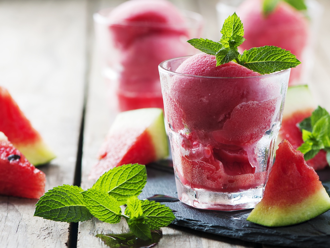 Фруктовое мороженое в стакане на столе с кусочками арбуза и мятой