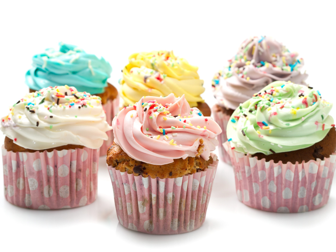 Сладкие кексы с кремом и посыпкой на белом фоне