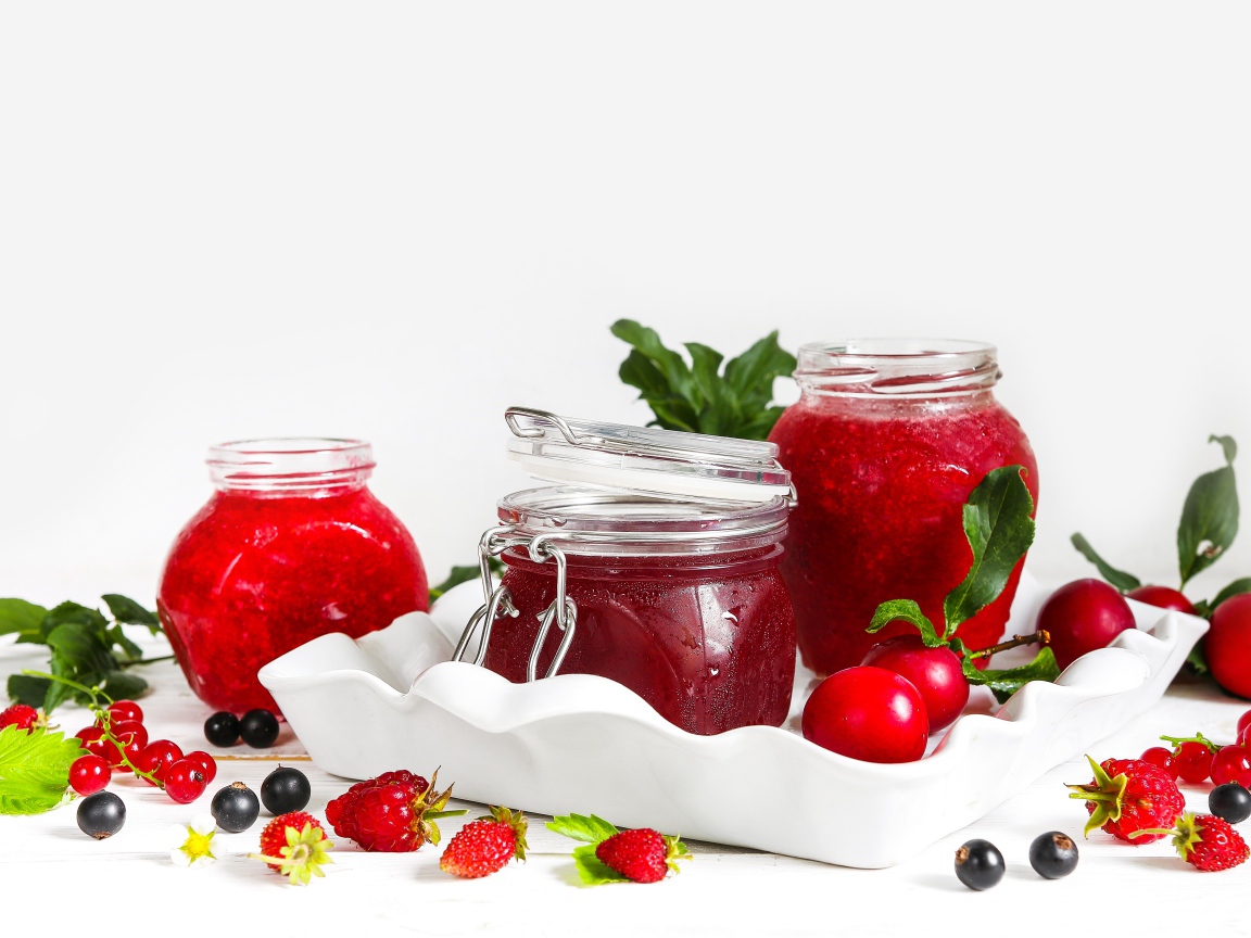 Три банки джема с ягодами на белом фоне