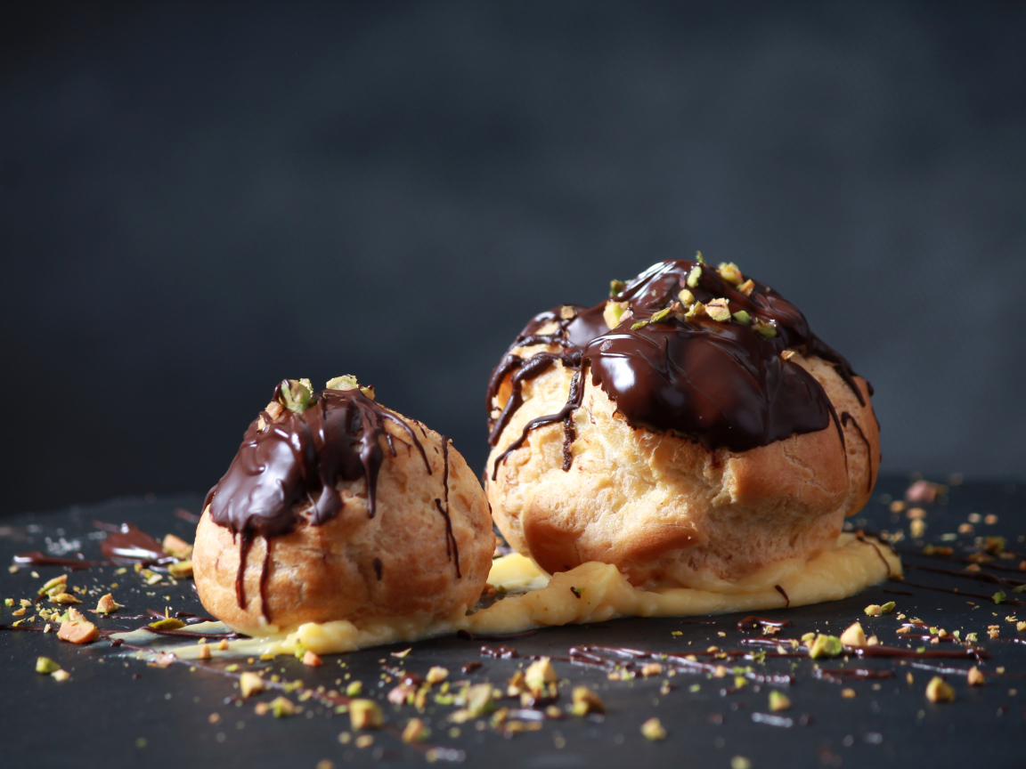 Два заварных пирожных с шоколадом на сером фоне