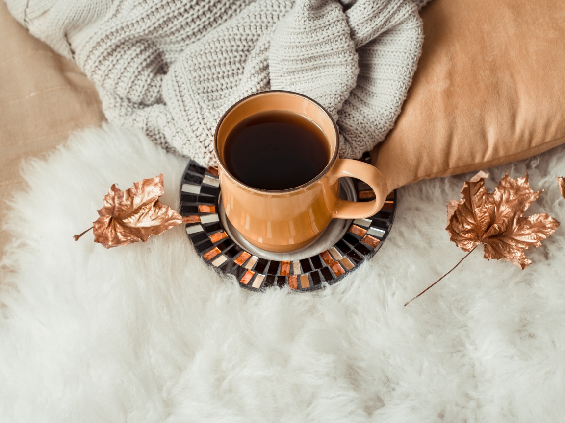 Чашка кофе стоит на покрывале с теплым свитером 