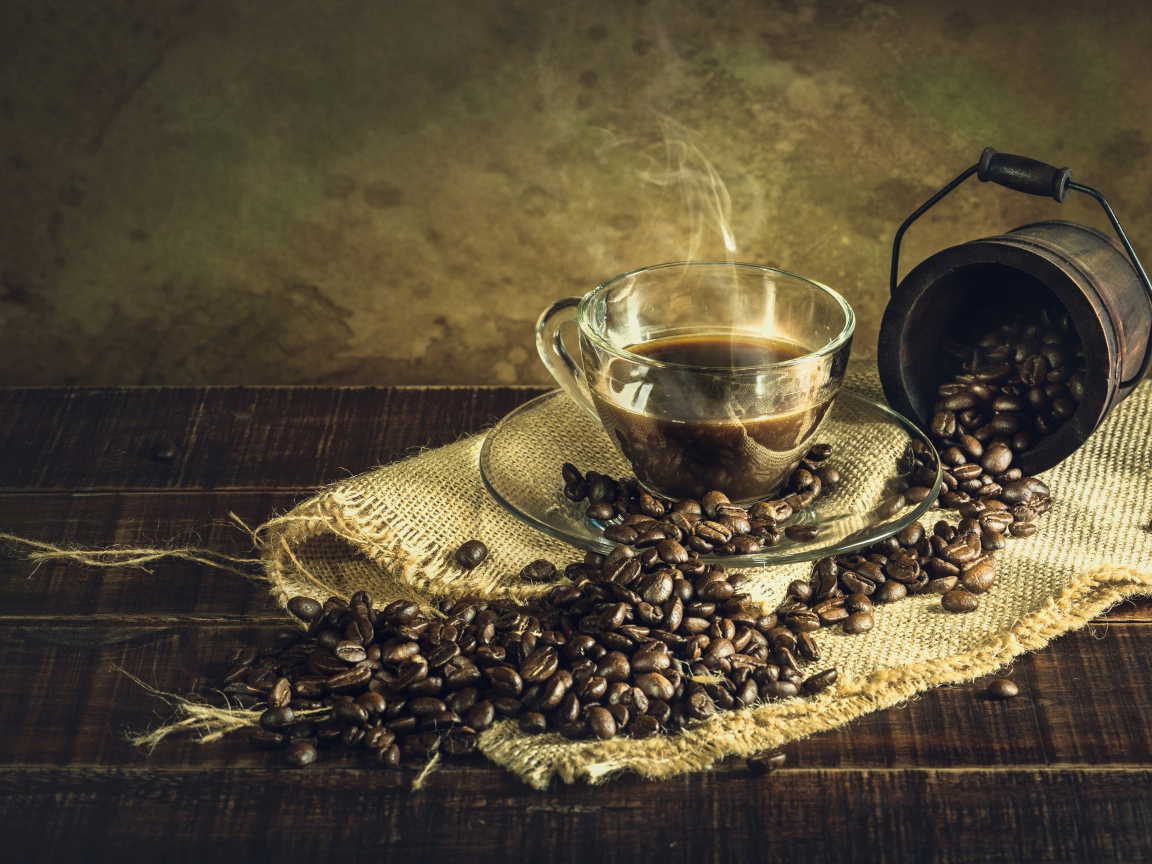 Чашка горячего крепкого кофе на столе с зернами