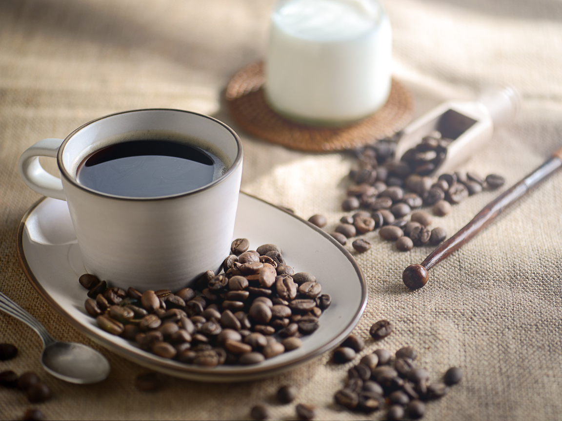 Чашка крепкого кофе на столе с зернами