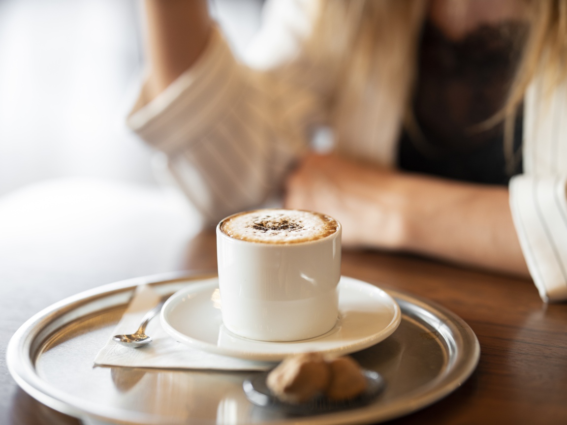 Чашка капучино с корицей на столе в кафе