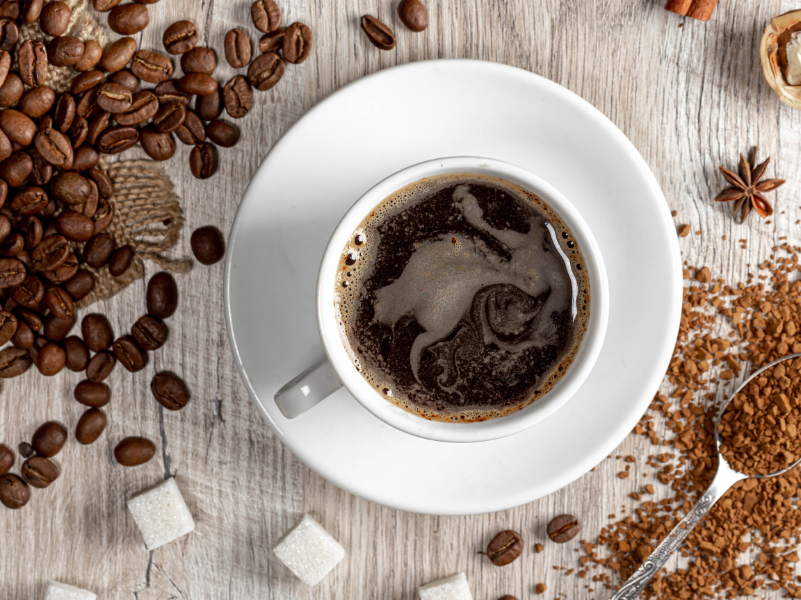 Чашка кофе на столе с сахаром и кофейными зернами