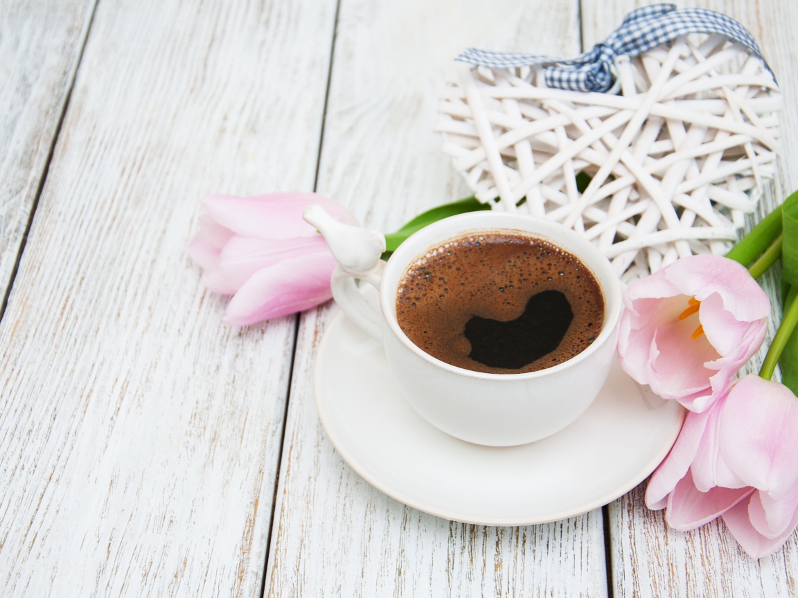 Чашка кофе на столе с розовыми тюльпанами и плетеным сердцем