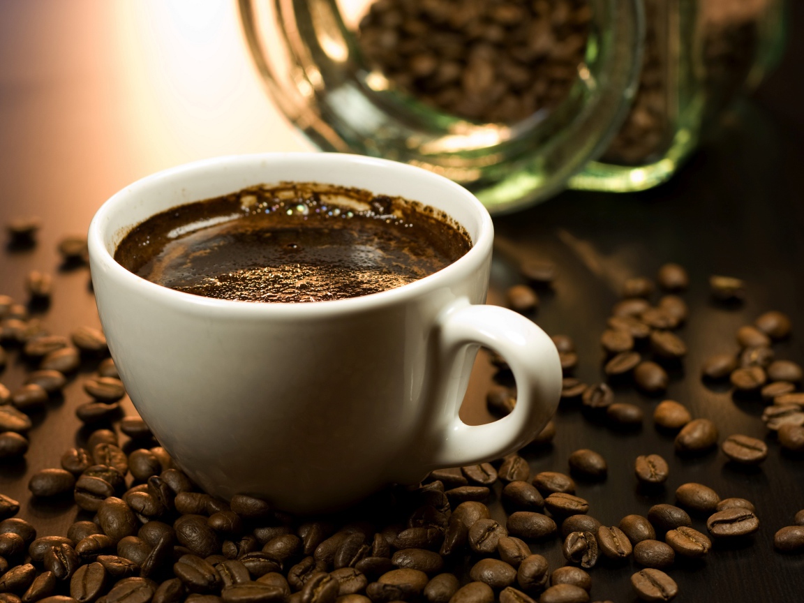 Чашка горячего кофе на столе с зернами