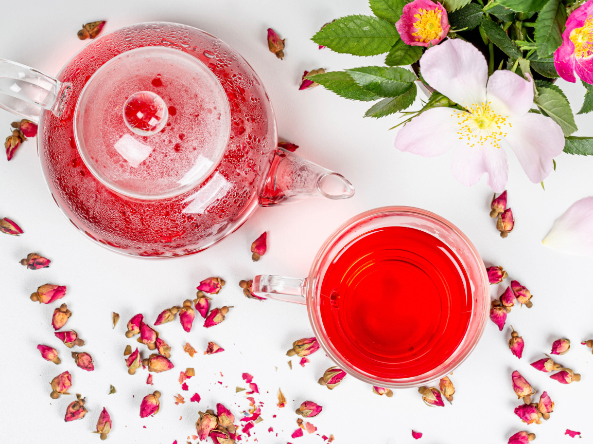 Свежий чай с шиповника в стеклянной чашке на столе с чайником