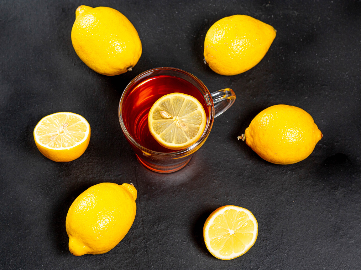 Стеклянная чашка чая с лимоном на сером столе 