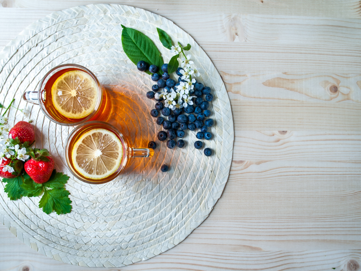 Чай с лимоном на столе с ягодами клубники и черники