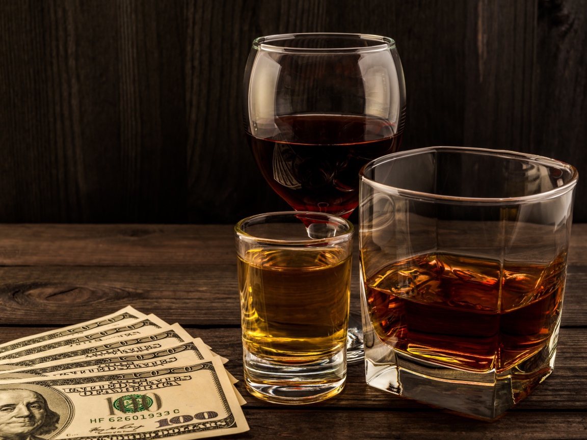 Три сосуда  с виски на столе с долларами