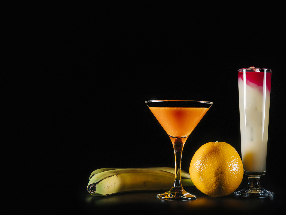 Два коктейля на черном фоне в бананом и апельсином