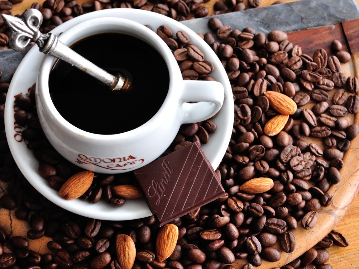 Белая чашка кофе на столе с кофейными зернами 