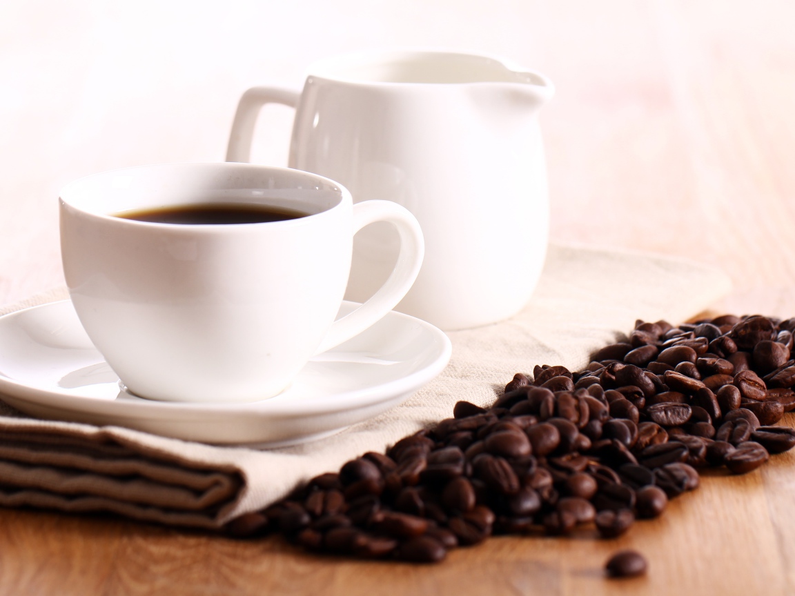 Белая чашка кофе на столе с молоком и зернами