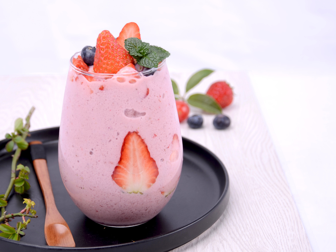 Йогурт в стакане с ягодами черники и клубники