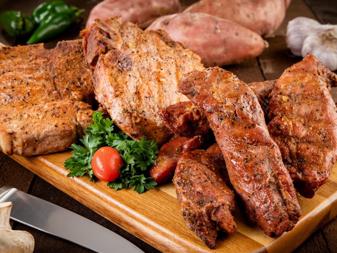 Аппетитное запеченное мясо на столе с чесноком и картофелем