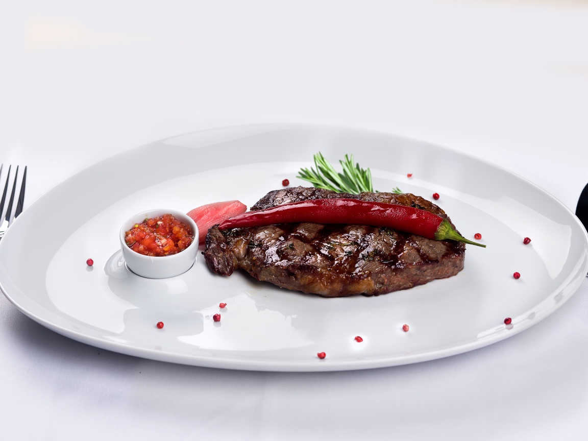 Стейк с кровью на тарелке с красным перцем