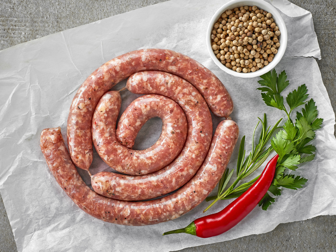 Домашняя колбаса на столе с зеленью и перцем