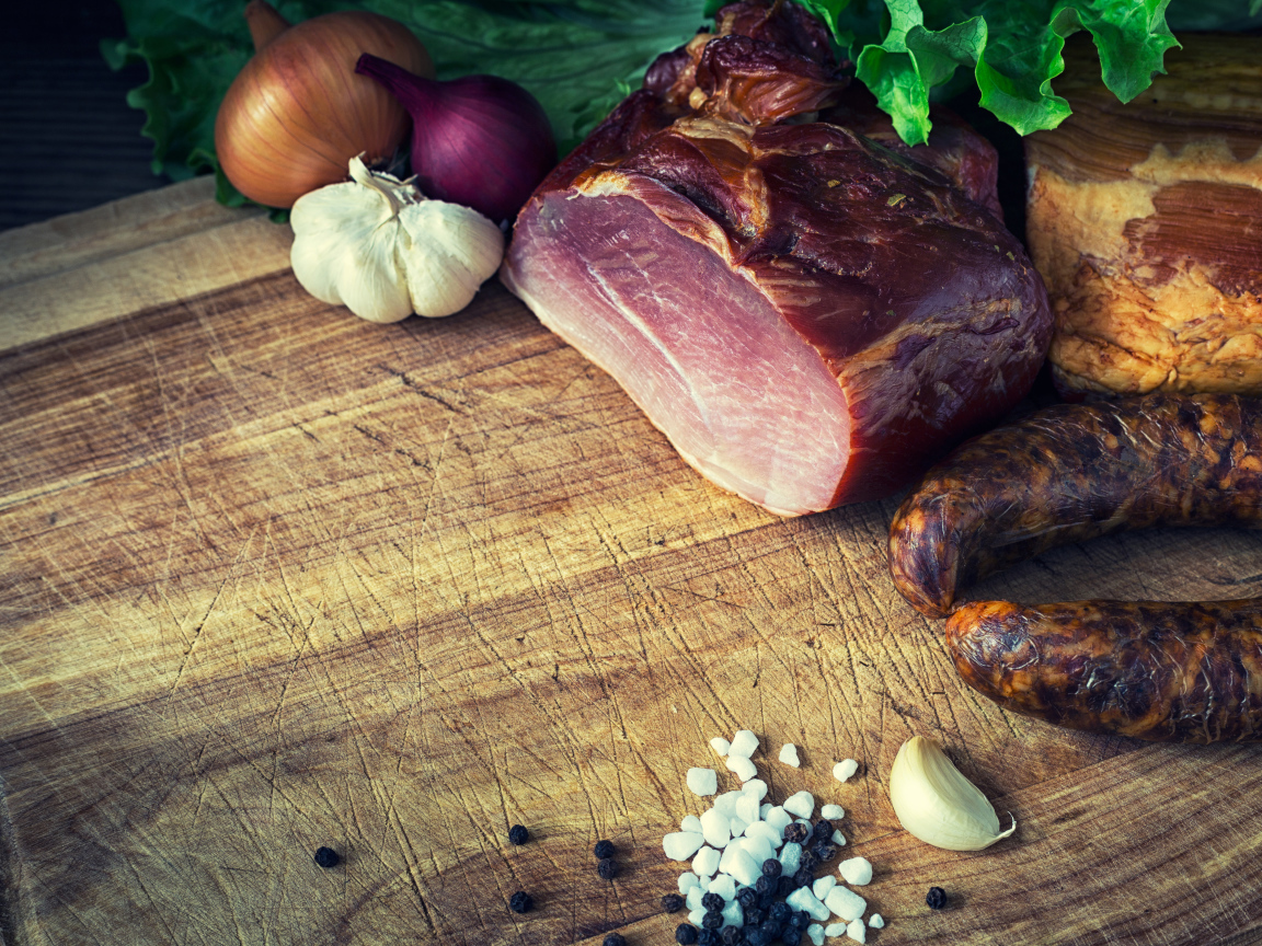 Мясные продукты на столе со специями, луком и чесноком 