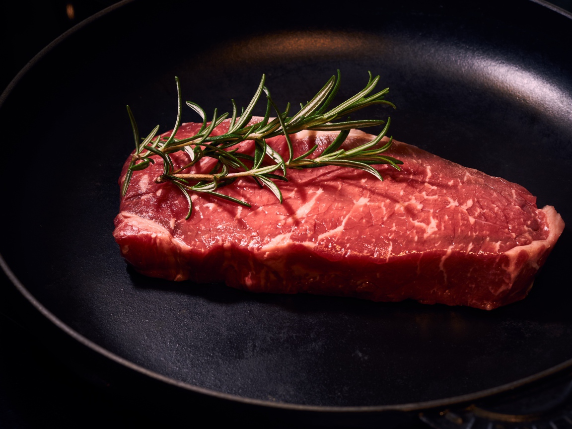 Кусок мяса на сковороде с розмарином