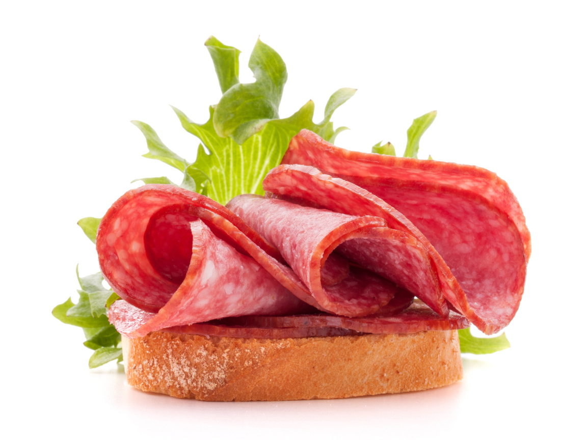 Бутерброд с листьями салата и колбасой на белом фоне