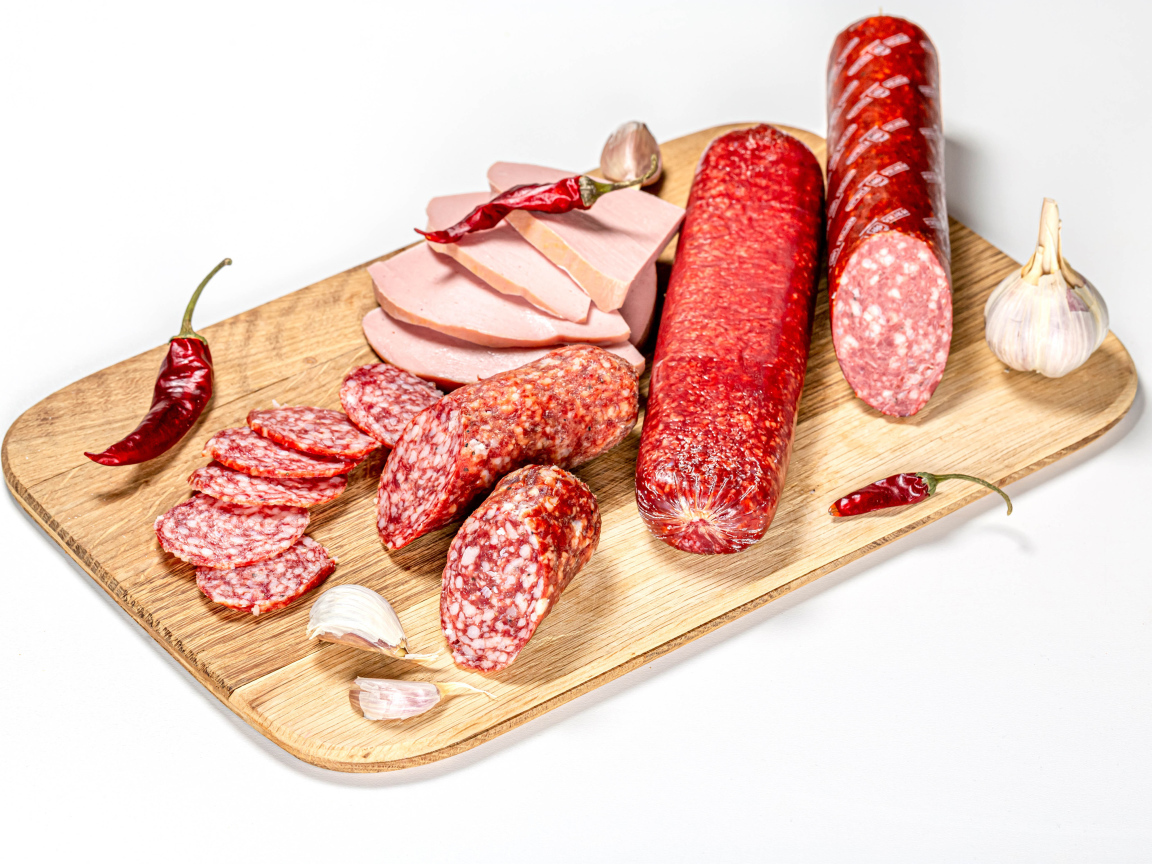 Вкусная колбаса с красным перцем и чесноком на доске на белом фоне