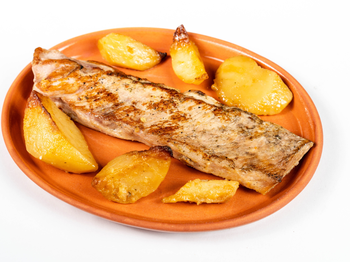 Кусок запеченной рыбы на тарелке с картофелем 