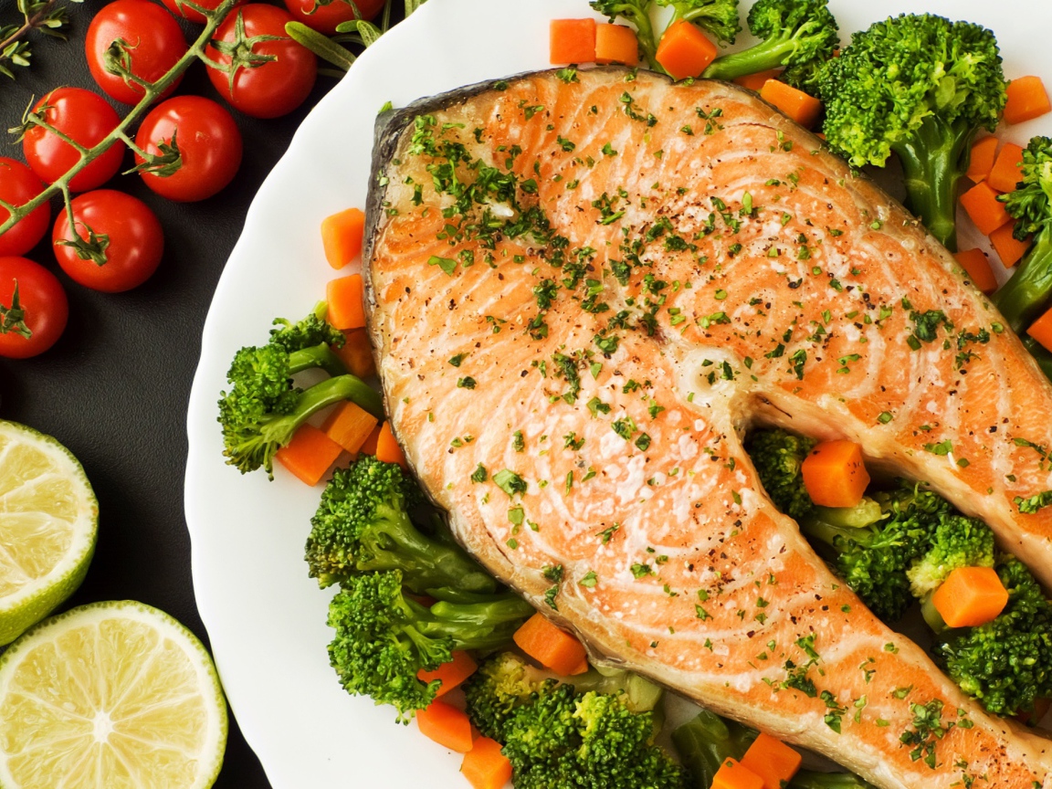 Кусок красной рыбы на тарелке с морковью и брокколи 