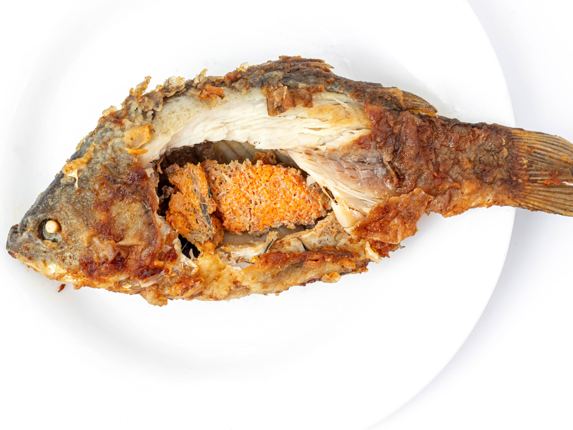 Жареная рыба с икрой внутри на белом фоне