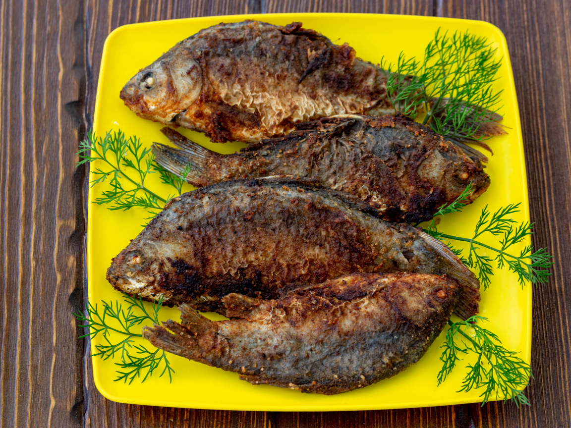 Grilled crucian with dill on a yellow plate