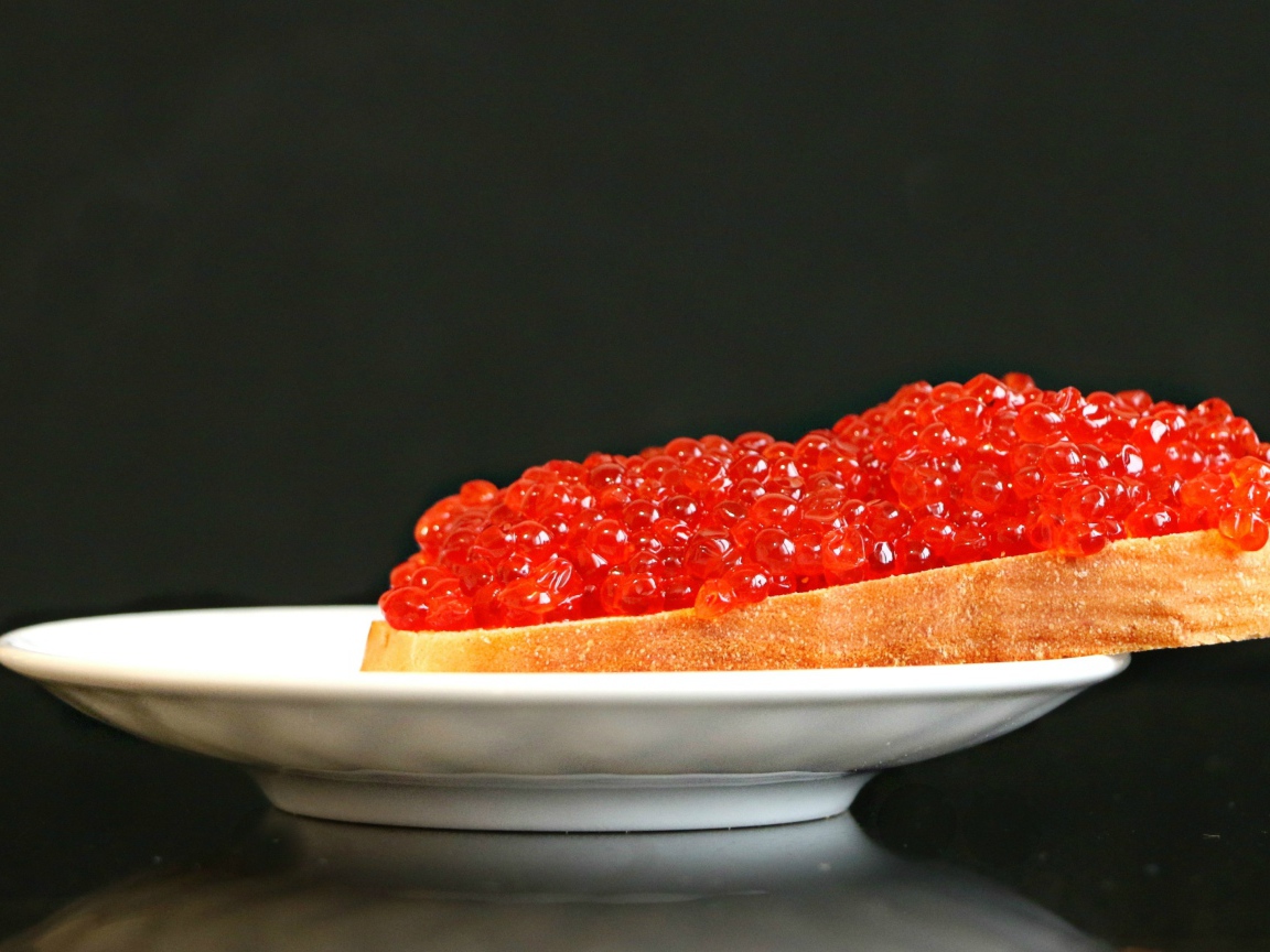 Бутерброд с красной икрой на белой тарелке 