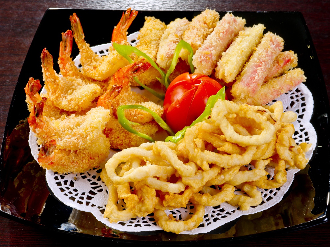 Морепродукты в кляре на тарелке с помидором