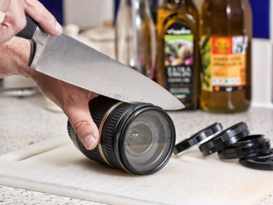 Мужчина нарезает ножом объектив фотоаппарата 