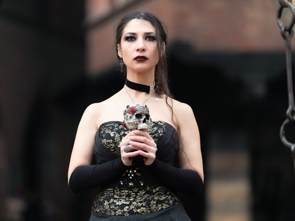 Gothic girl with a glass - a skull in her hands