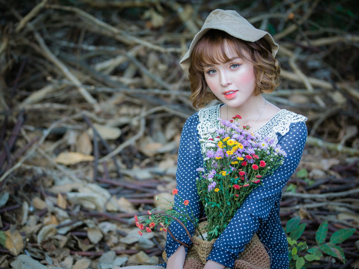 Молодая девушка азиатка с букетом цветов сидит на ветках