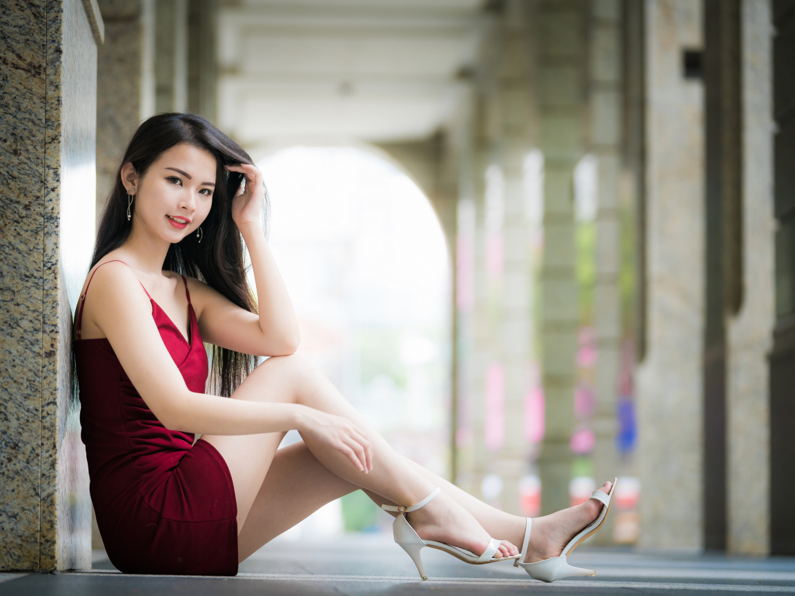 Девушка азиатка в красном платье сидит на полу