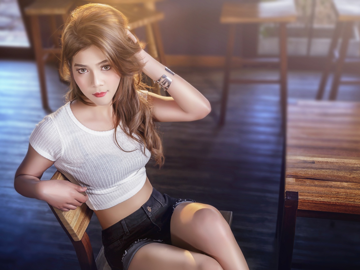 Девушка азиатка сидит на деревянном стуле в кафе