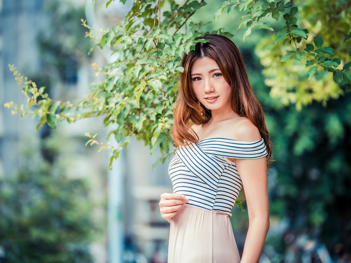 Девушка азиатка стоит под деревом в парке 