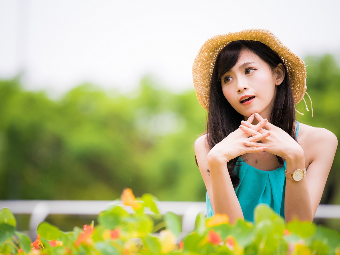 Девушка азиатка с часами на руке в шляпе