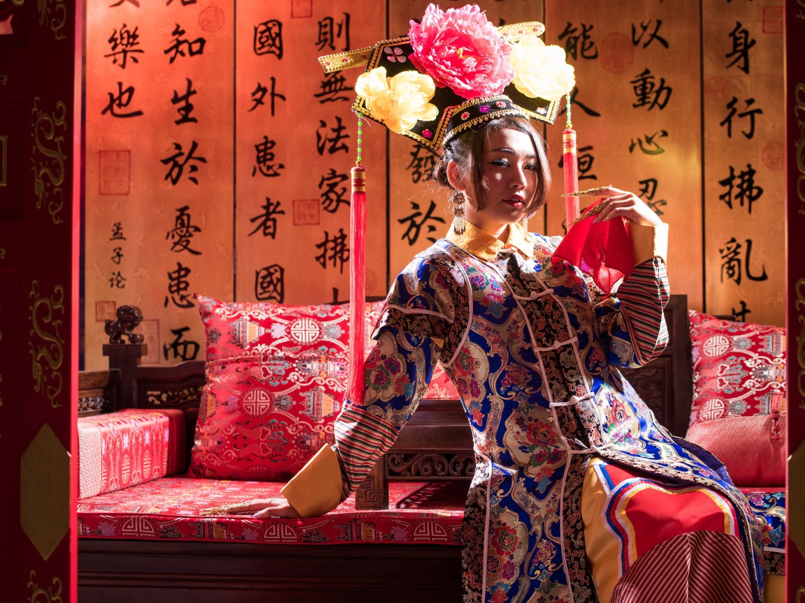 Красивая девушка азиатка в национальном костюме на диване