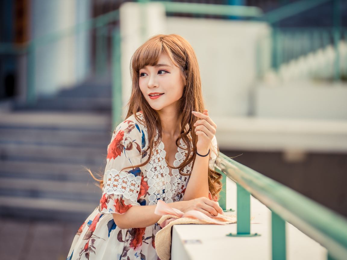 Красивая девушка азиатка стоит у перил 