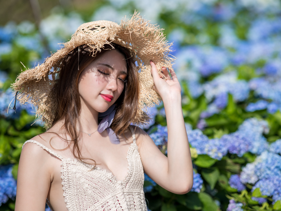 Красивая девушка азиатка с закрытыми глазами на фоне цветов гортензии